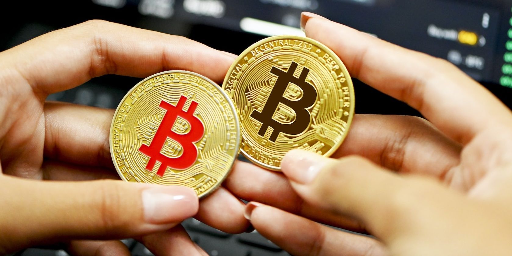two hands holding red and black bitcoin tokens