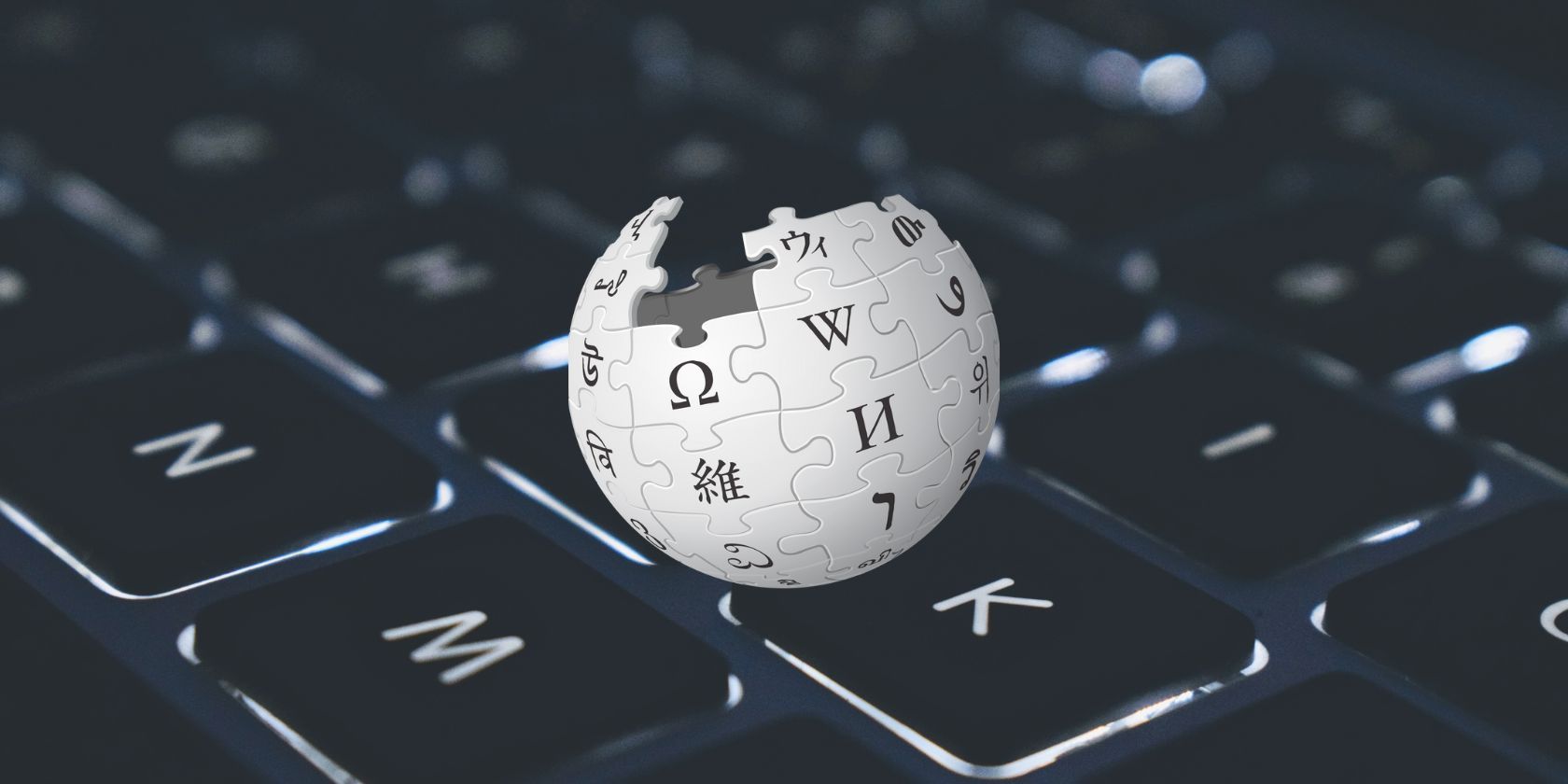 An image of the Wikipedia logo in front of a keyboard background