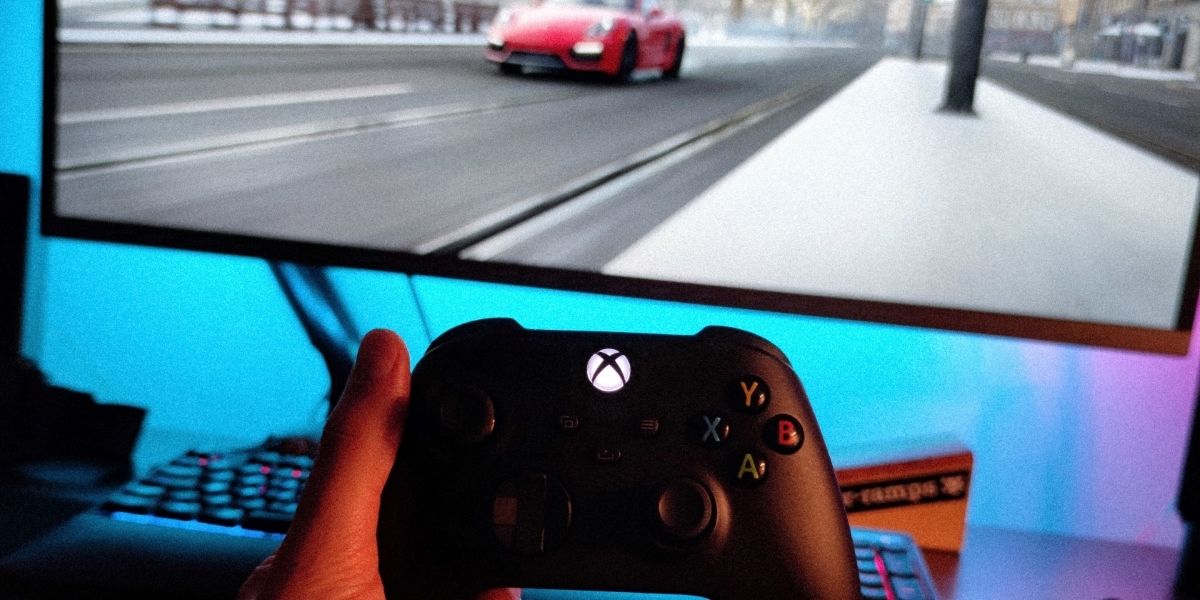 A photo of a standard Xbox Series X controller in front of a monitor 
