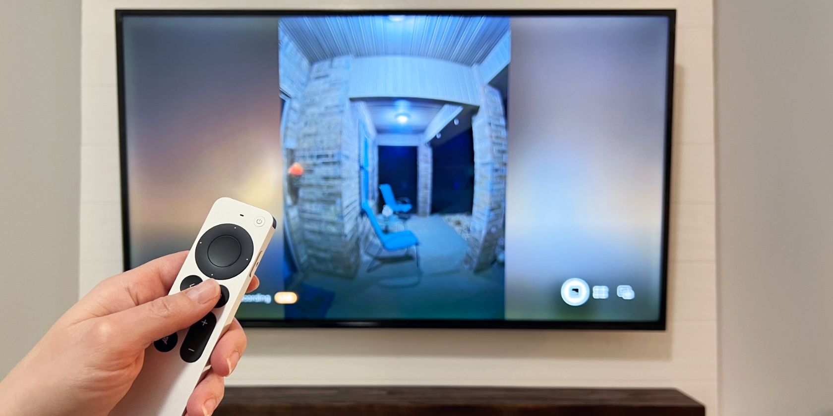 Siri Remote in hand controlling a HomeKit camera on an Apple TV 4K.
