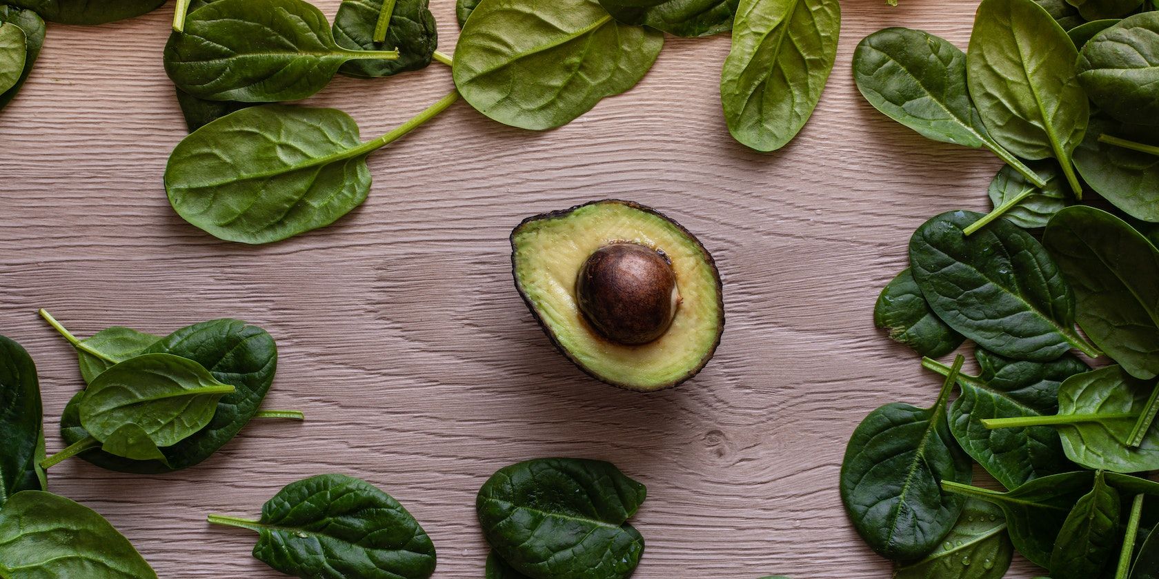 Half avocado surrounded by spinach leaves