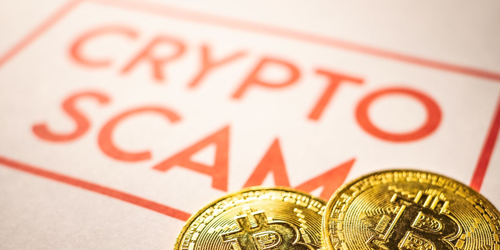gold bitcoins next to crypto scam sign on paper