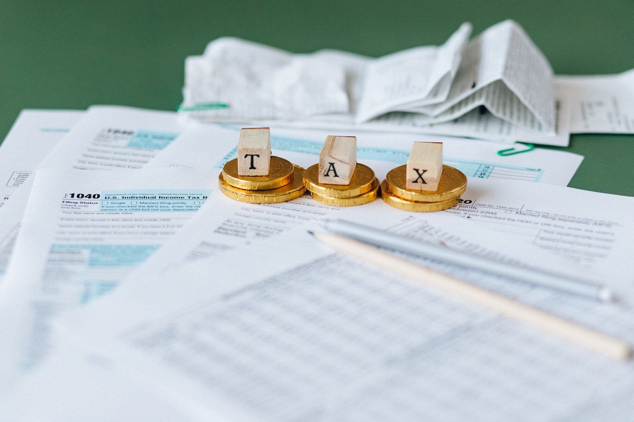 Tax marked dice and crypto coins on top of tax documents on a table.