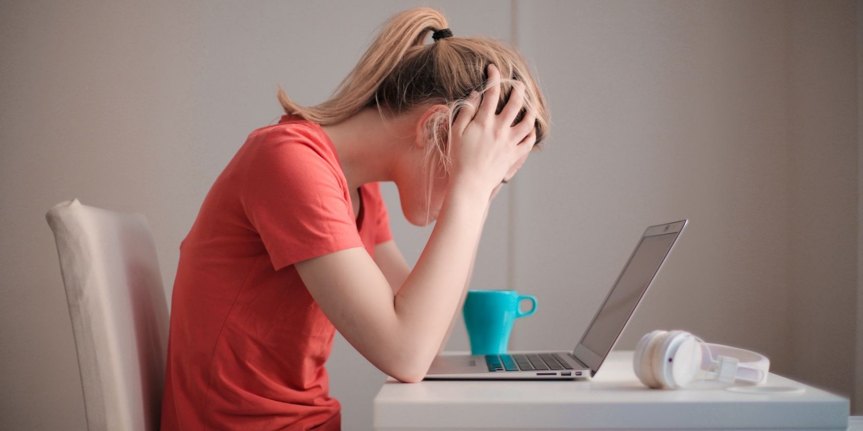 Girl with a pony tail holding her head in frustration in front of her laptop
