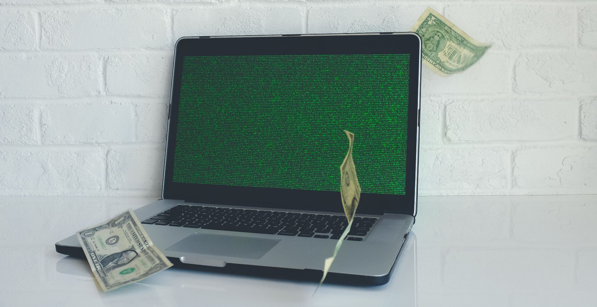 billetes de dólar cayendo en una laptop con pantalla verde