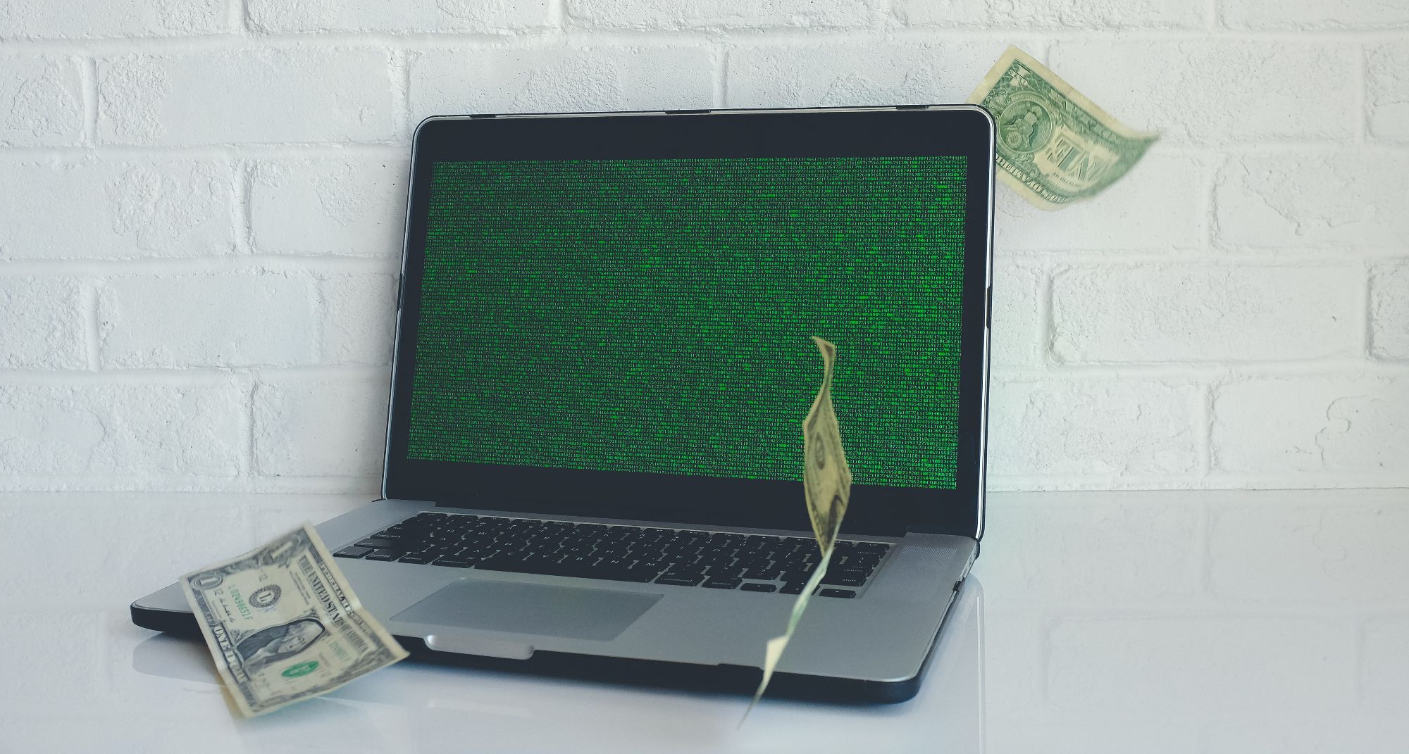 green matrix screen on laptop with falling dollar bills surrounding