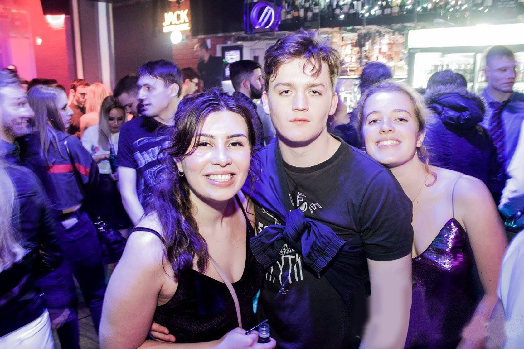 Three people posing in a nightclub.