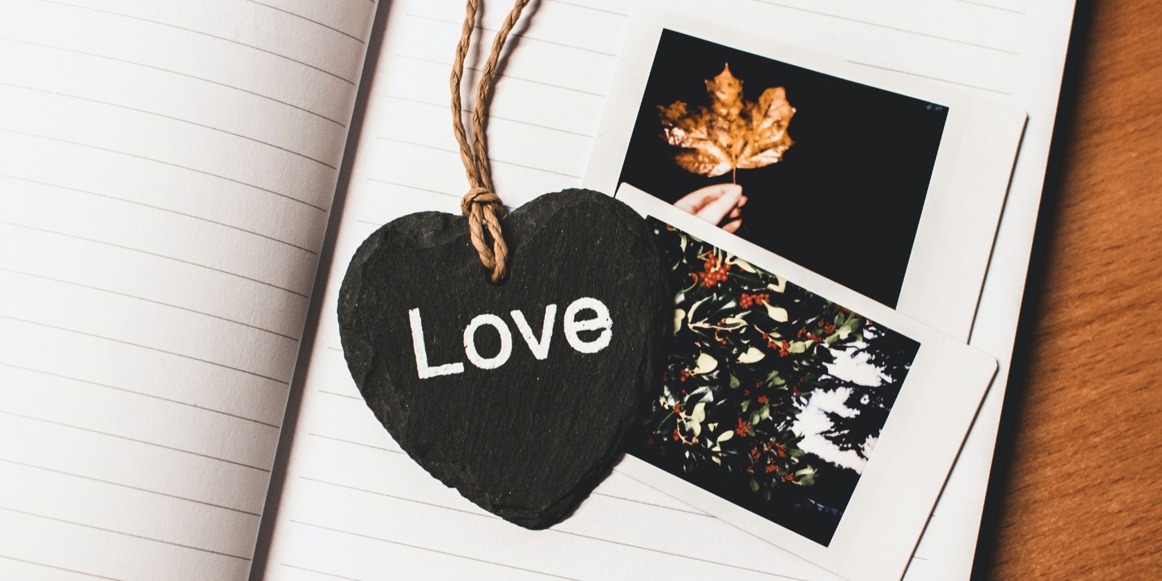 Heart shaped 'Love' bookmark on top of two polaroids in an open book
