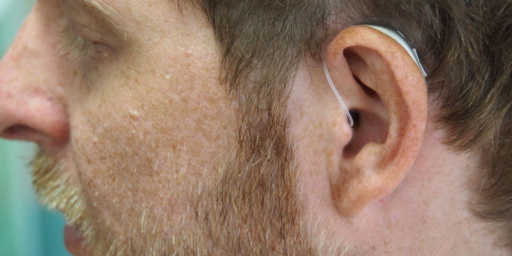 Close-up of man wearing hearing aid device behind ear
