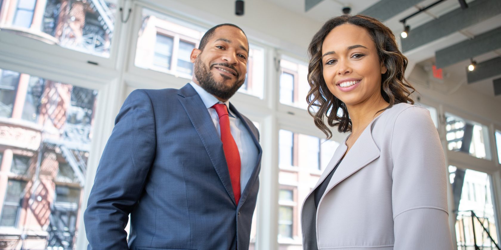 man and woman in corporate attire smiling 