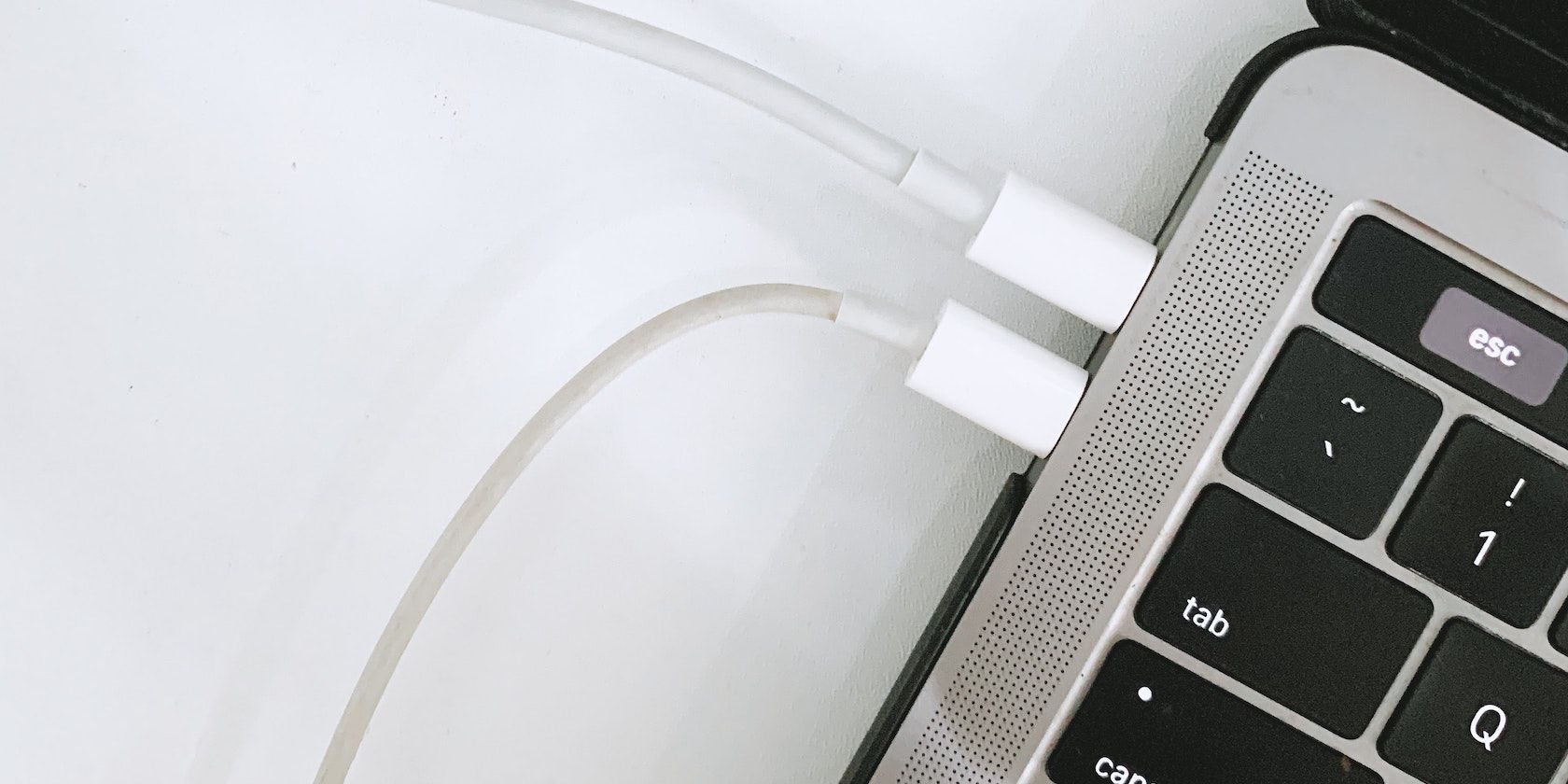 An Apple laptop with 2 USB-C cables plugged into its ports
