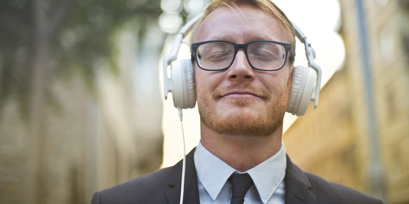 A man in formal wear enjoying music on headphones
