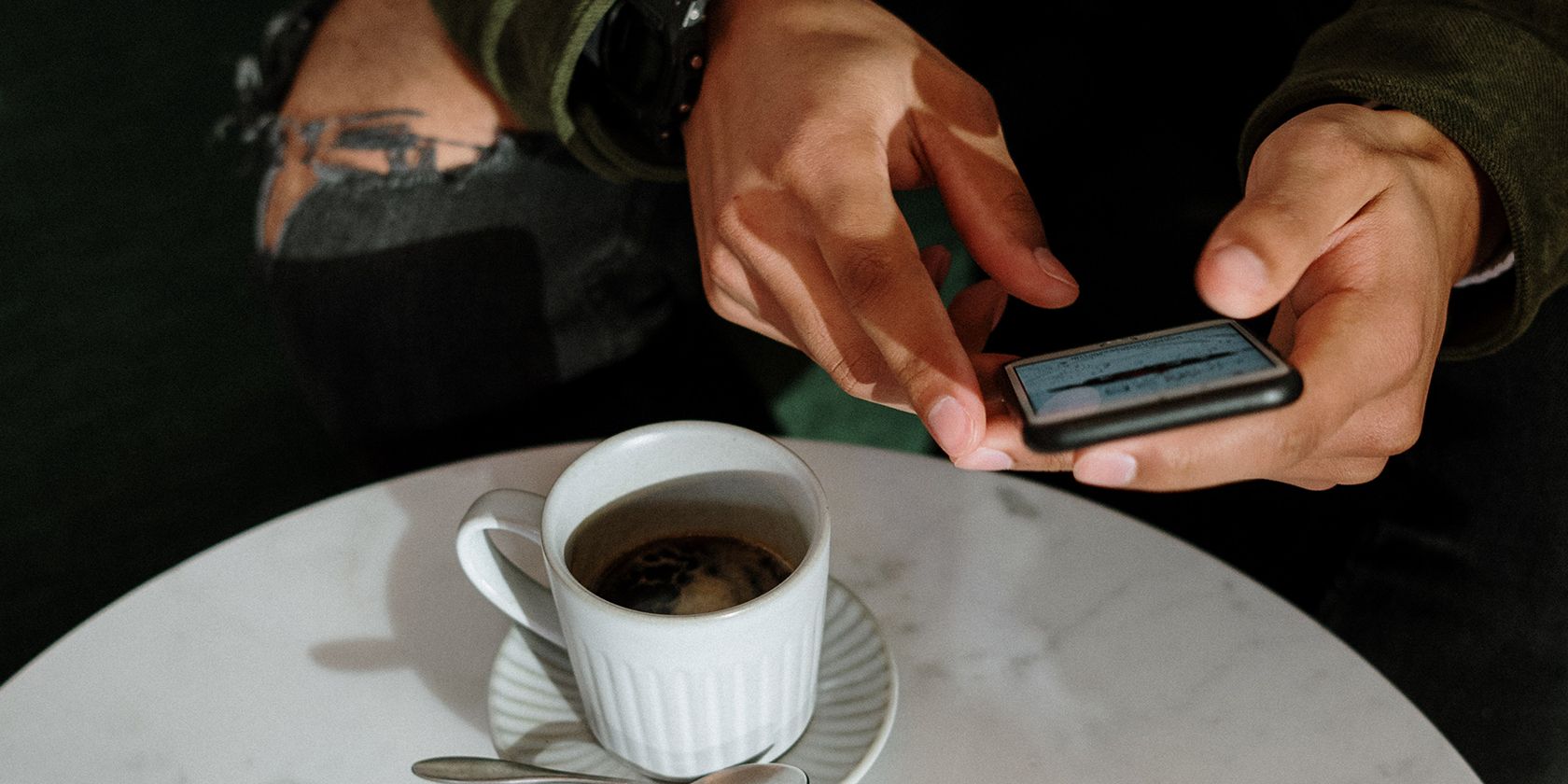 Hombre usando iPhone con café