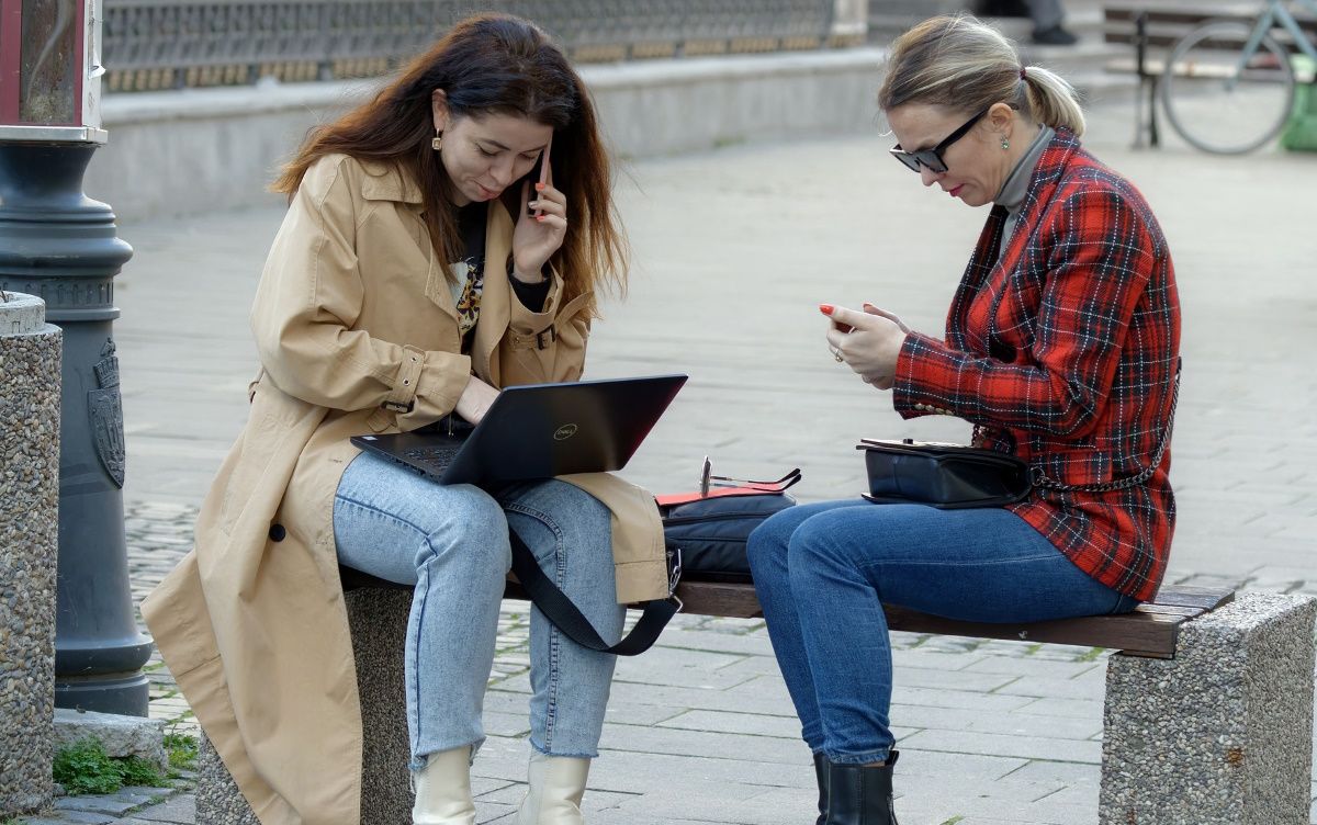 Two Women Using Public Network On a Laptop In a Park