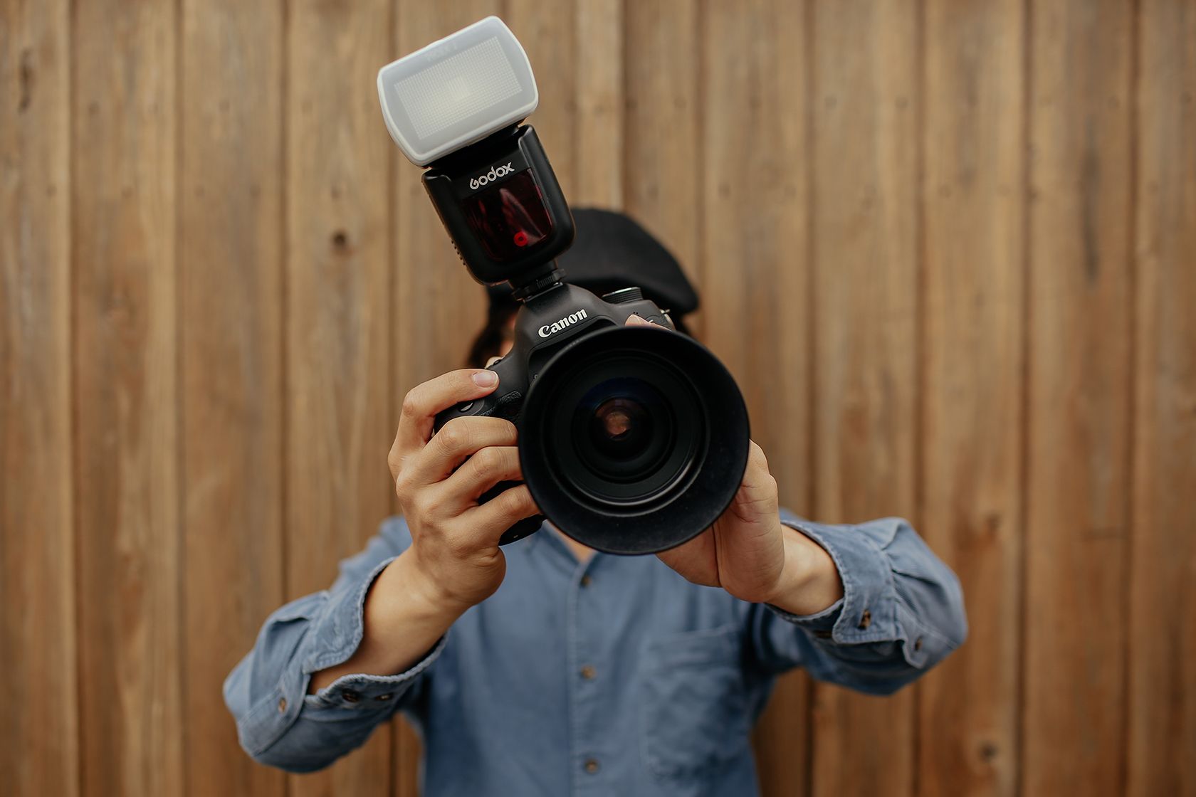 Man holding Canon DSLR with a wide angle lens and flashgun.