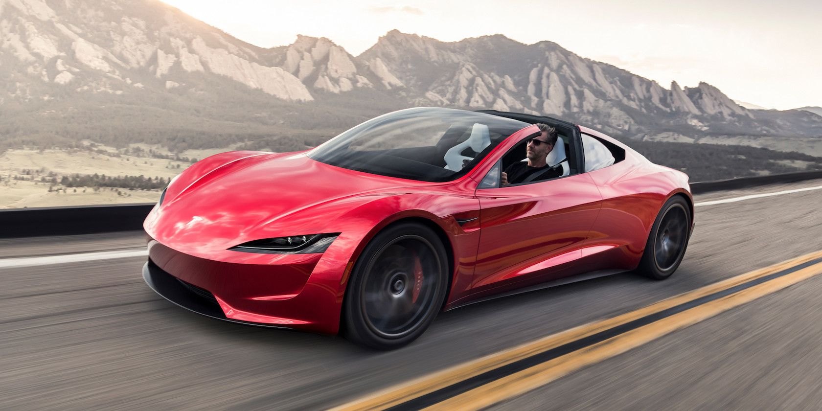 Roadster rojo de Tesla con montañas al fondo