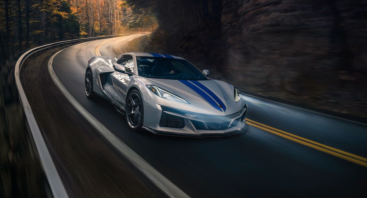 A silver and blue striped 2024 Corvette convertible driving on a winding road
