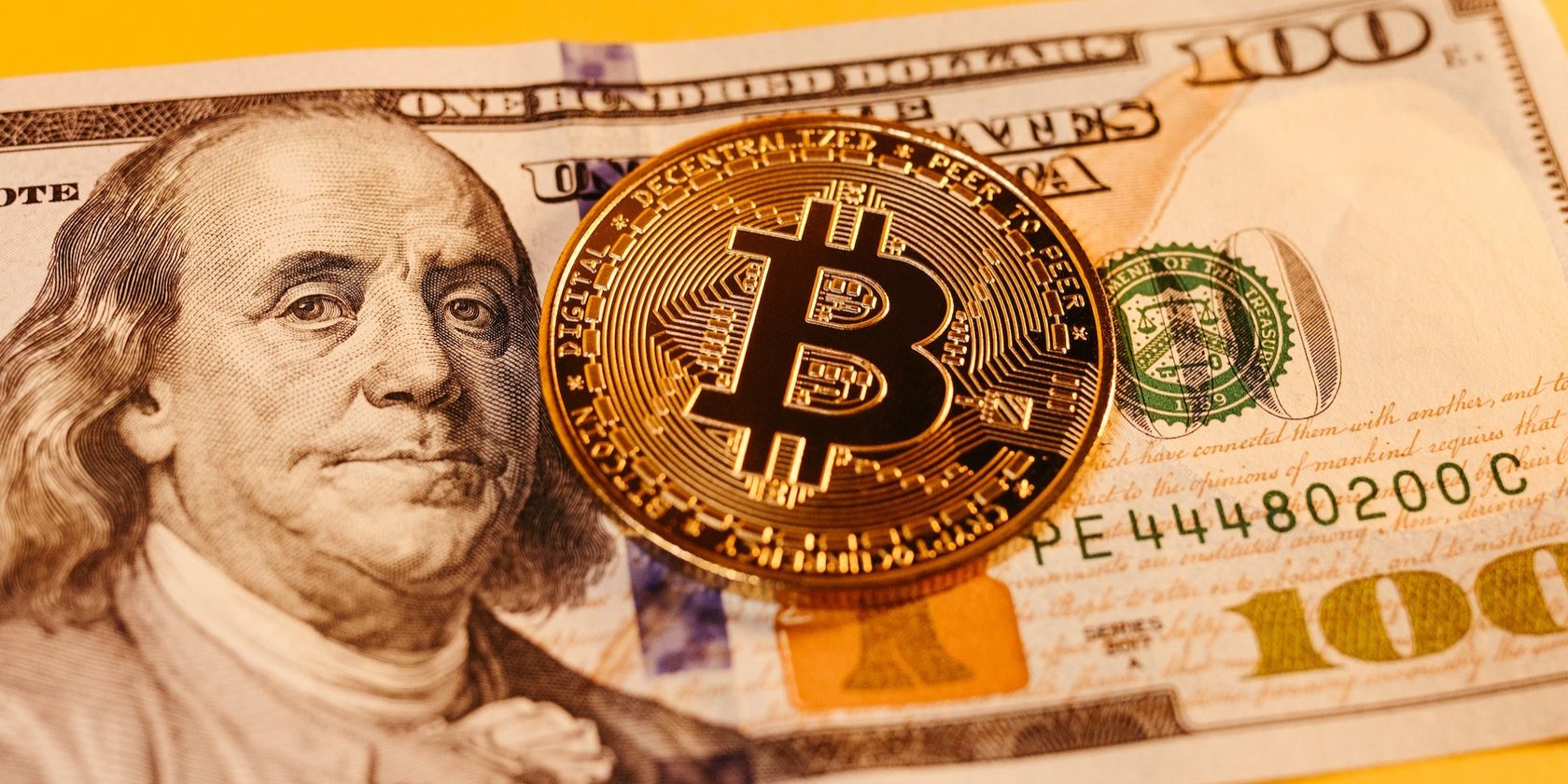 a picture of a bitcoin coin and a hundred dollar note