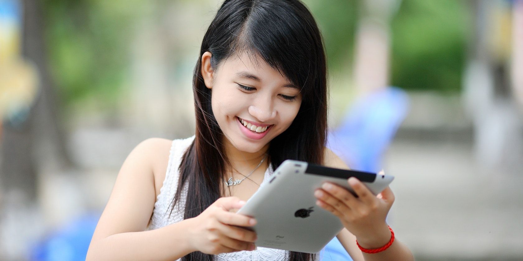 A woman holding white iPad and smiling