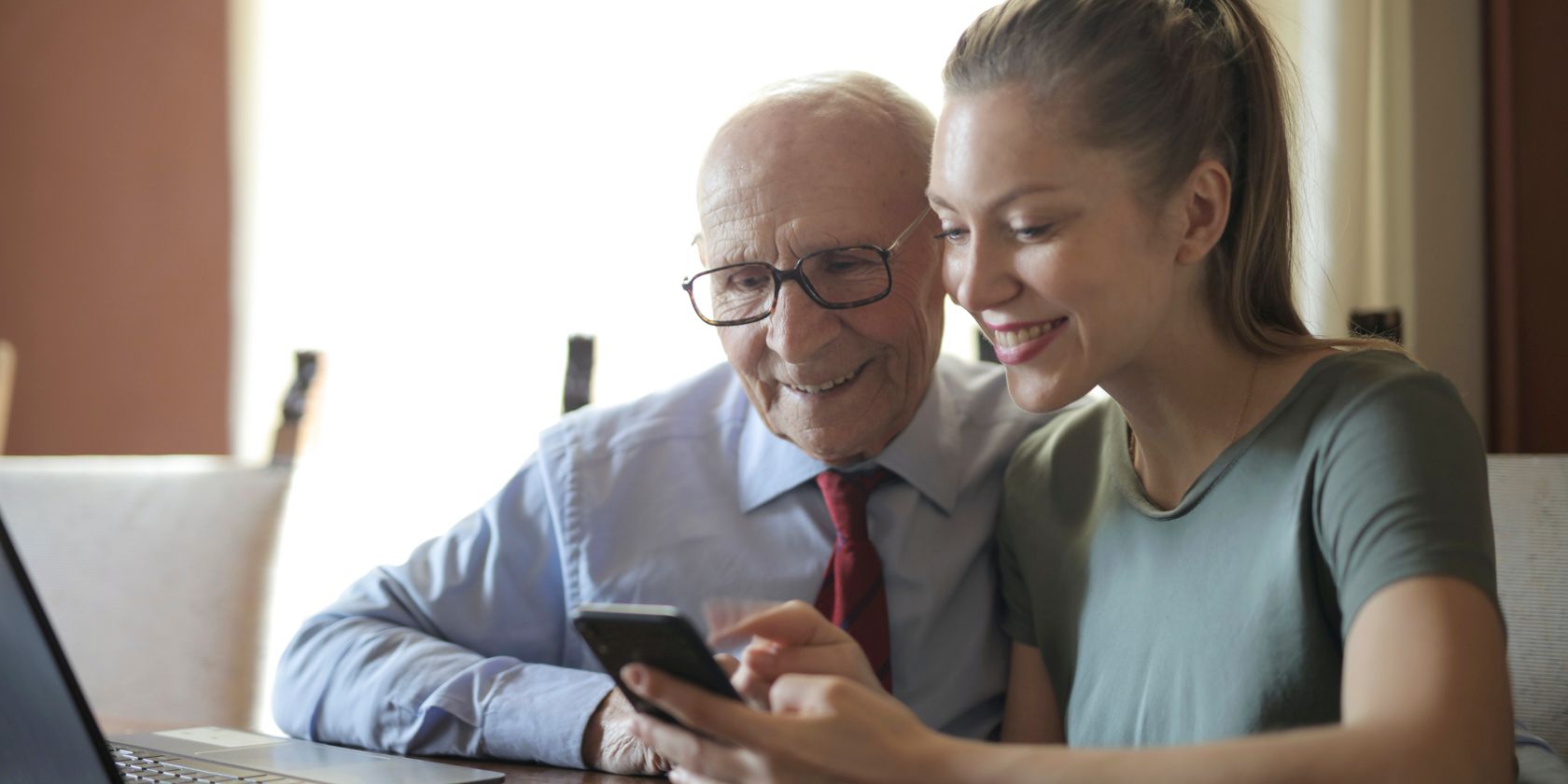 A younger woman and older man looking at a smartphone together