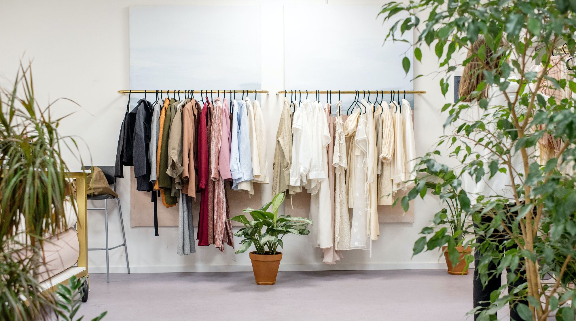 An image of a clothes rack in a store surrounded by plants