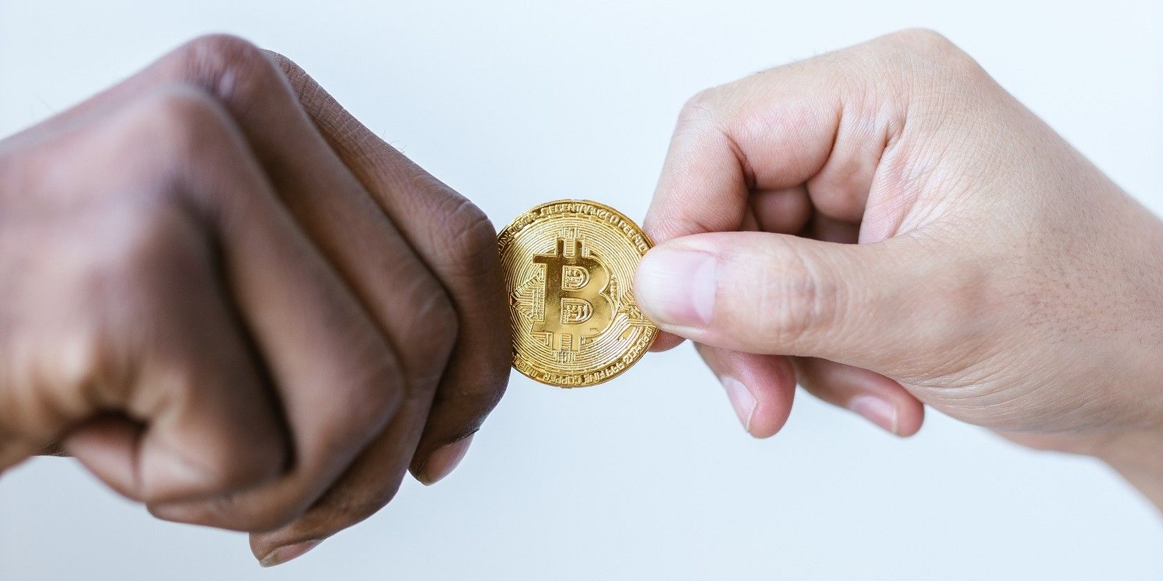 Close-Up Shot of Two People Holding a Bitcoin