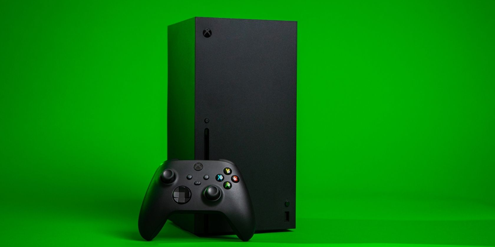 A photograph of an Xbox Series X console and controller in front of a bright green background