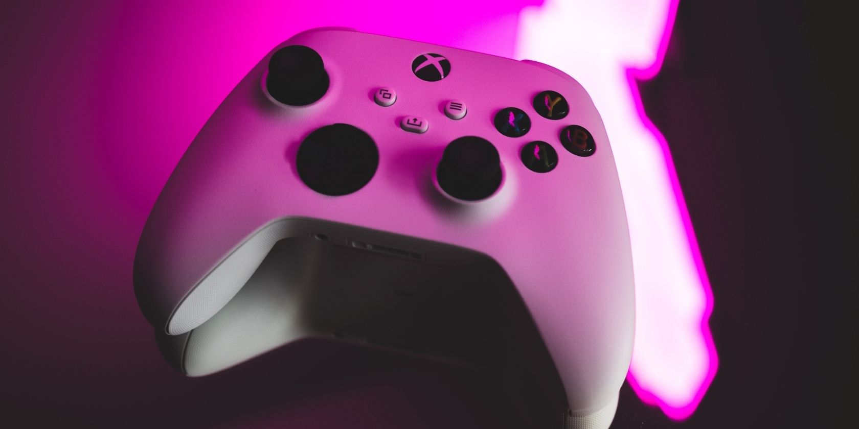 A photograph of a white Xbox Wireless Controller under a bright pink light 