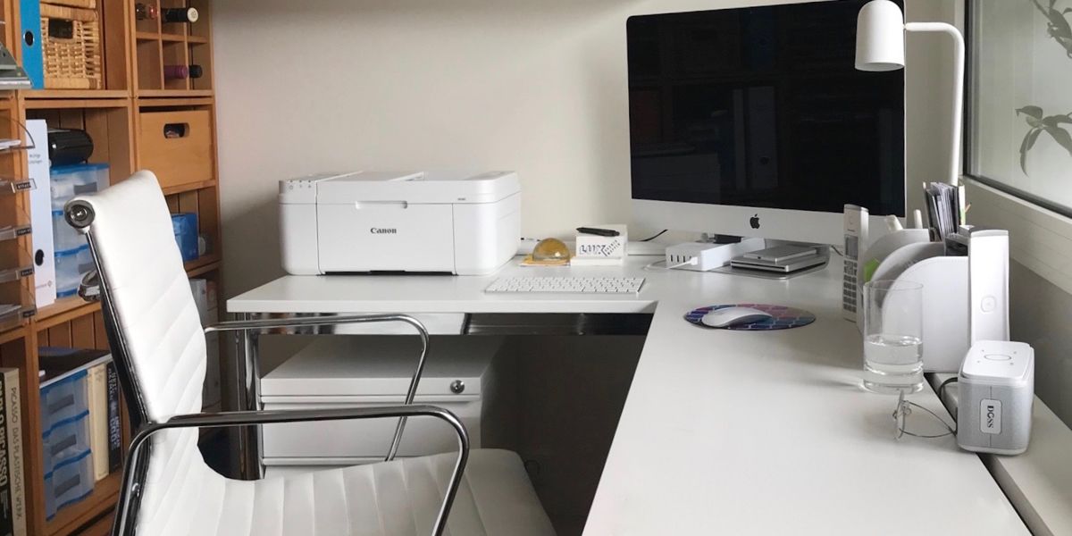 A home office setup with a desktop computer and a printer on a large desk.