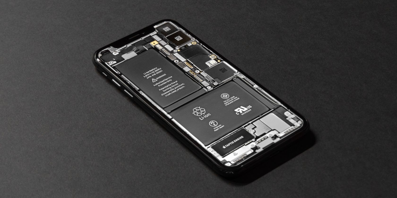 iPhone tanpa penutup belakang yang menampilkan bagian dalam dan baterai