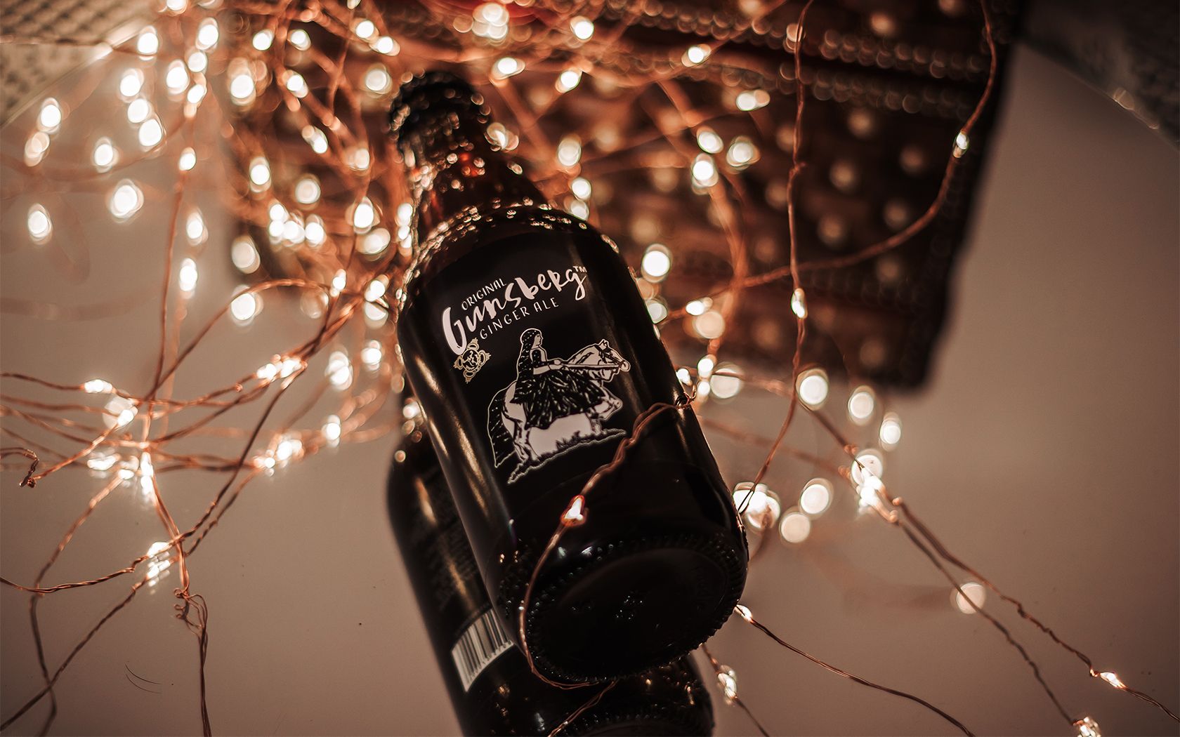 Alcohol bottle laying on fairy lights.