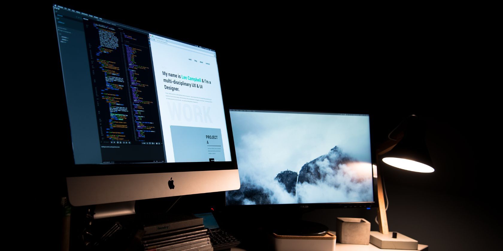 UX and UI designer's website portfolio shown on an iMac sitting beside a second computer screen and desk lamp 