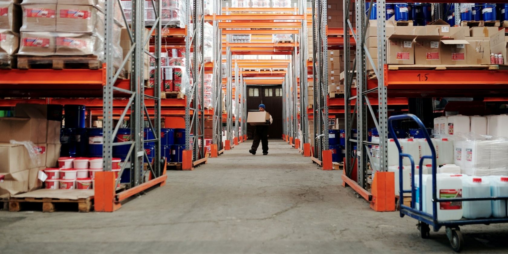 Person carrying a box in an aisle of a warehouse