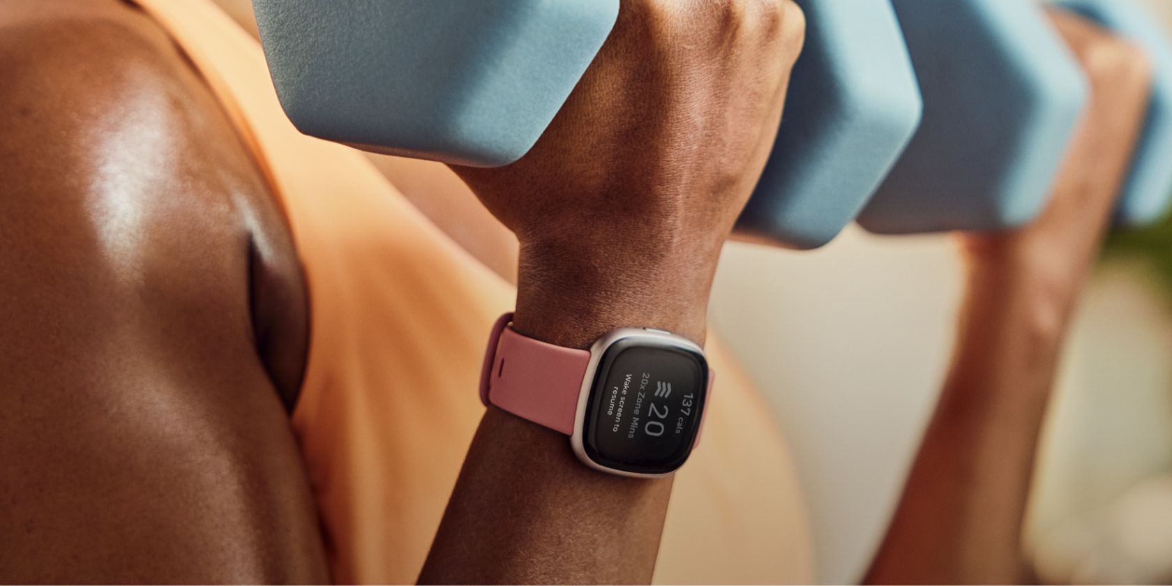Orang berolahraga sambil memakai jam tangan pintar Fitbit Versa 4