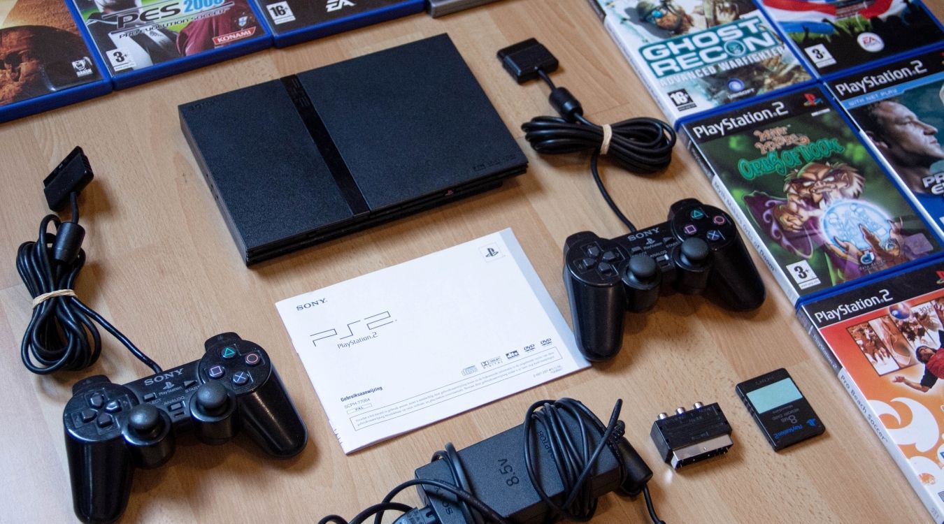 A photograph of a PlayStation 2 surrounded by accessories and software 