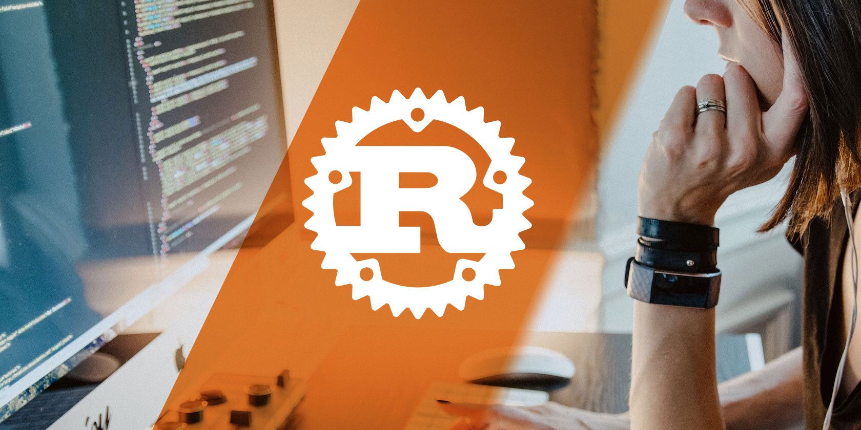 A Rust logo superimposed on a photograph of somebody working on an iMac desktop computer