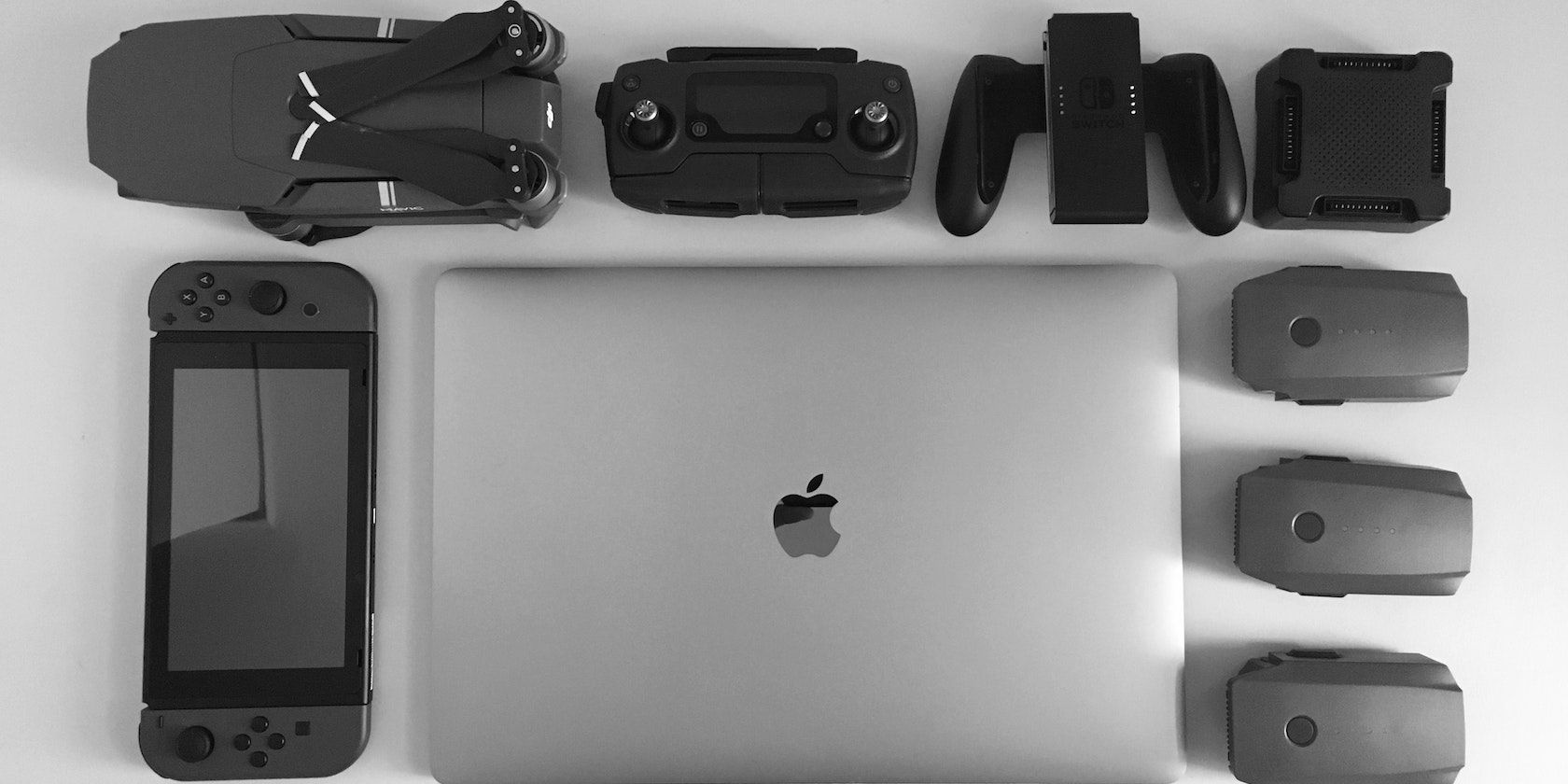 Silver MacBook surrounded by black electronic devices