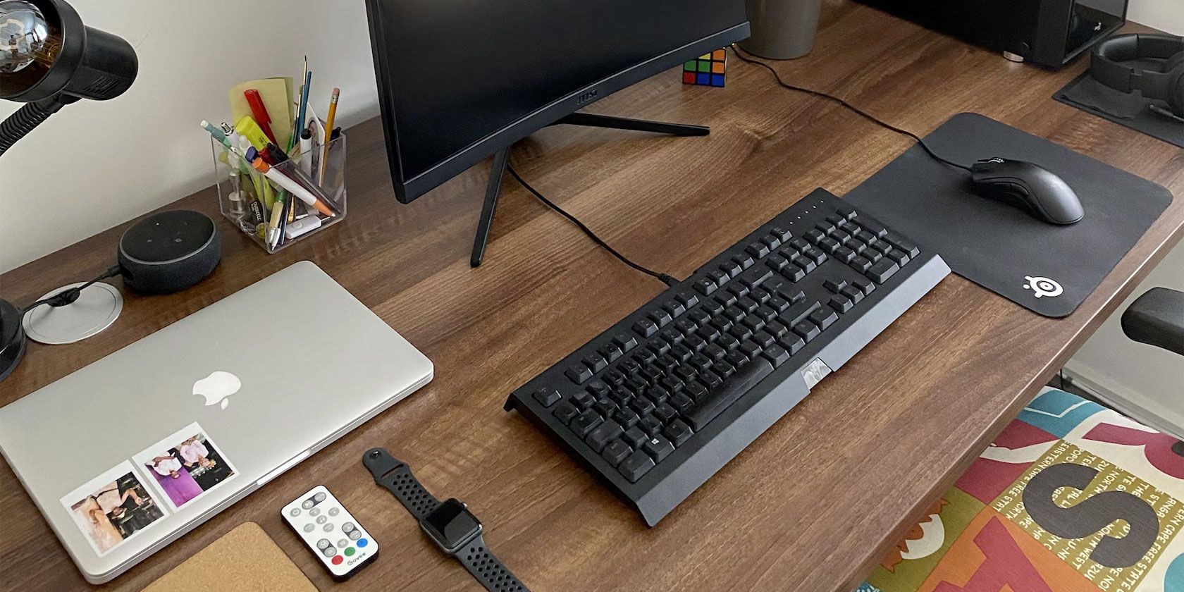 A desk with many objects including a laptop, keyboard, and Amazon Echo Dot