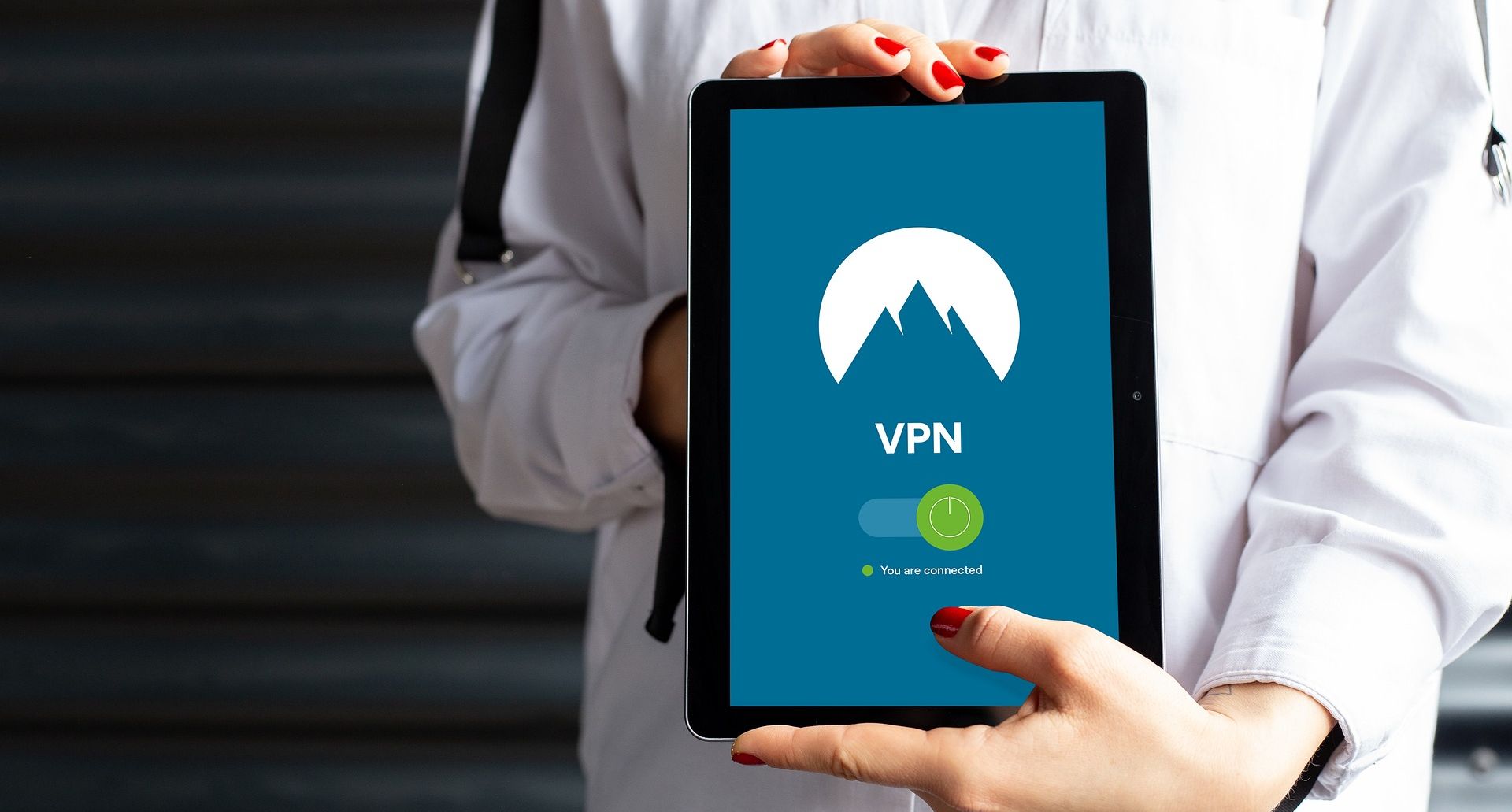 شخصی که تبلت در دست دارد با برنامه vpn فعال روی صفحه