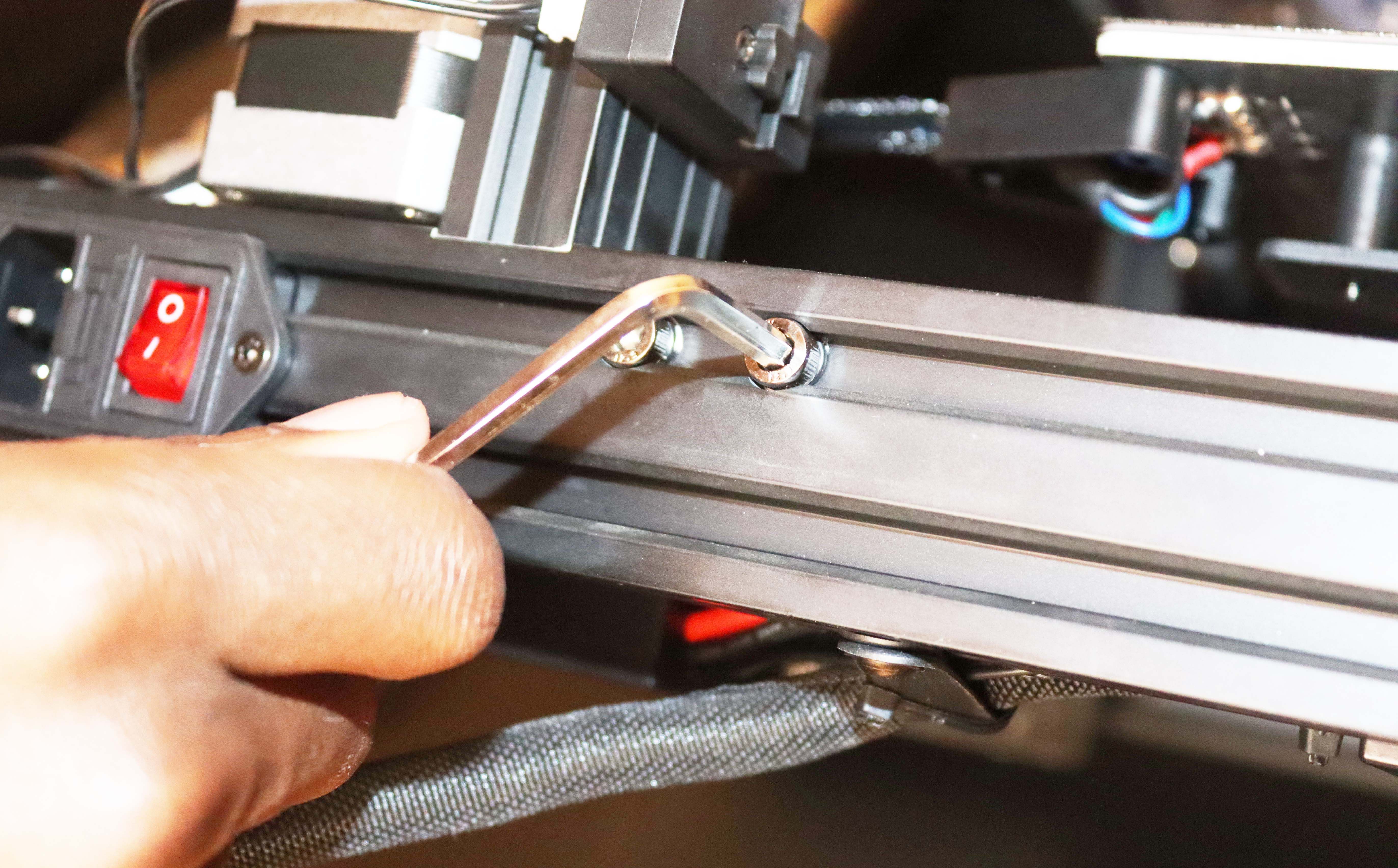 Using a wrench to tighten the screws on the base of the printer