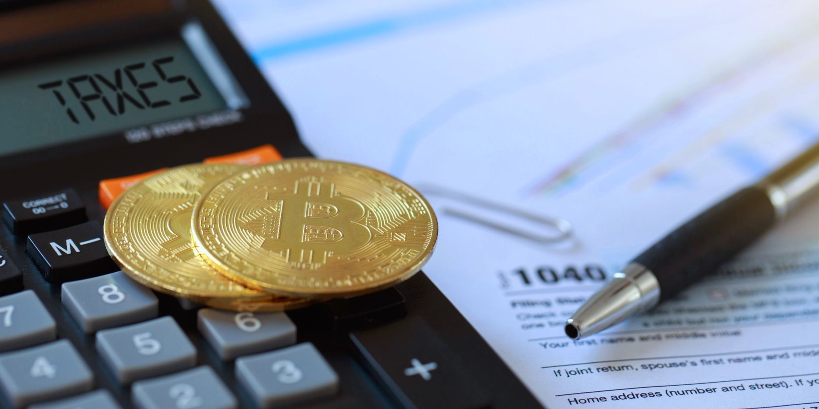 two bitcoins on a calculator on top of tax documents feature