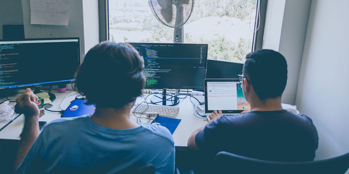 Deux programmeurs assis dans un bureau examinant du code.