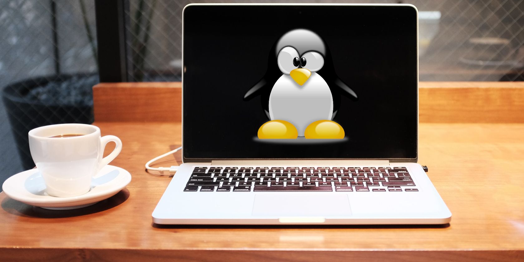 Màn hình máy tính xách tay có logo Linux và một tách trà ở bên cạnh