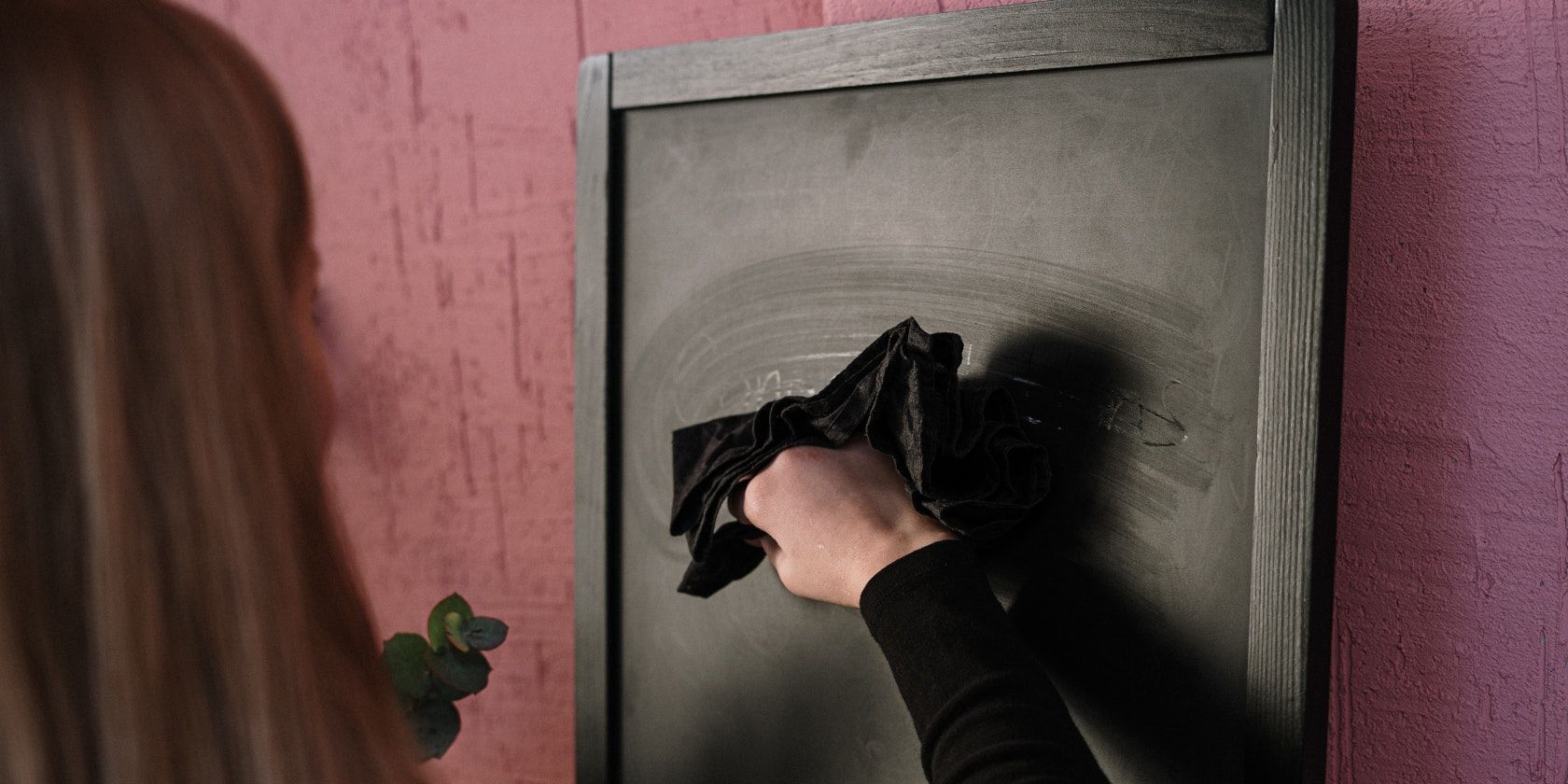 Woman erasing chalkboard using a cloth