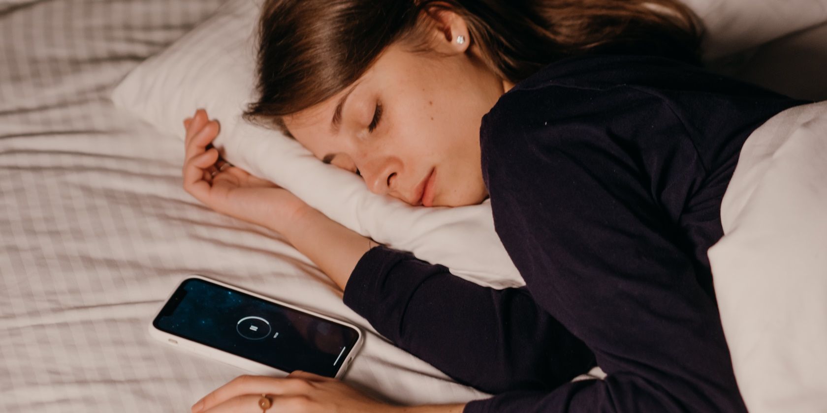 woman lying in bed and sleeping next to smartphone