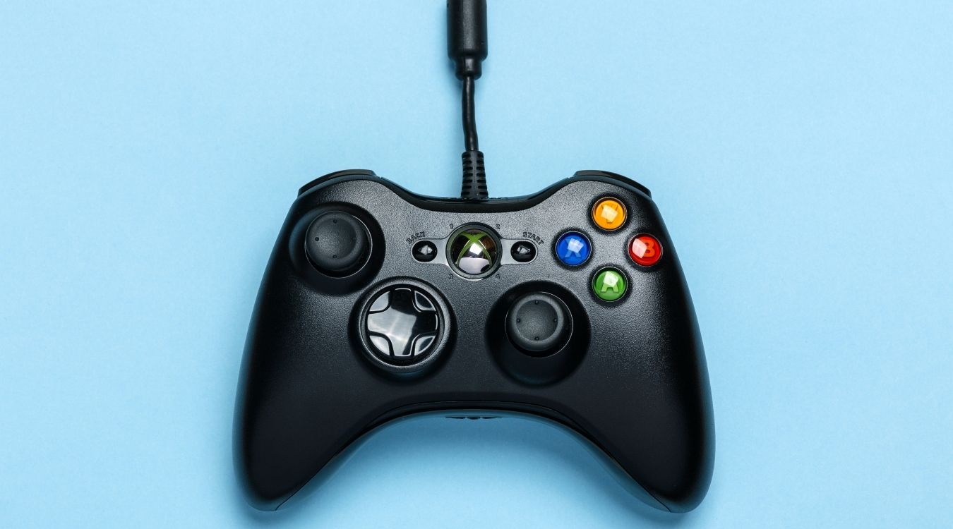 A photograph of a wired Xbox 360 controller in front of a blue background 