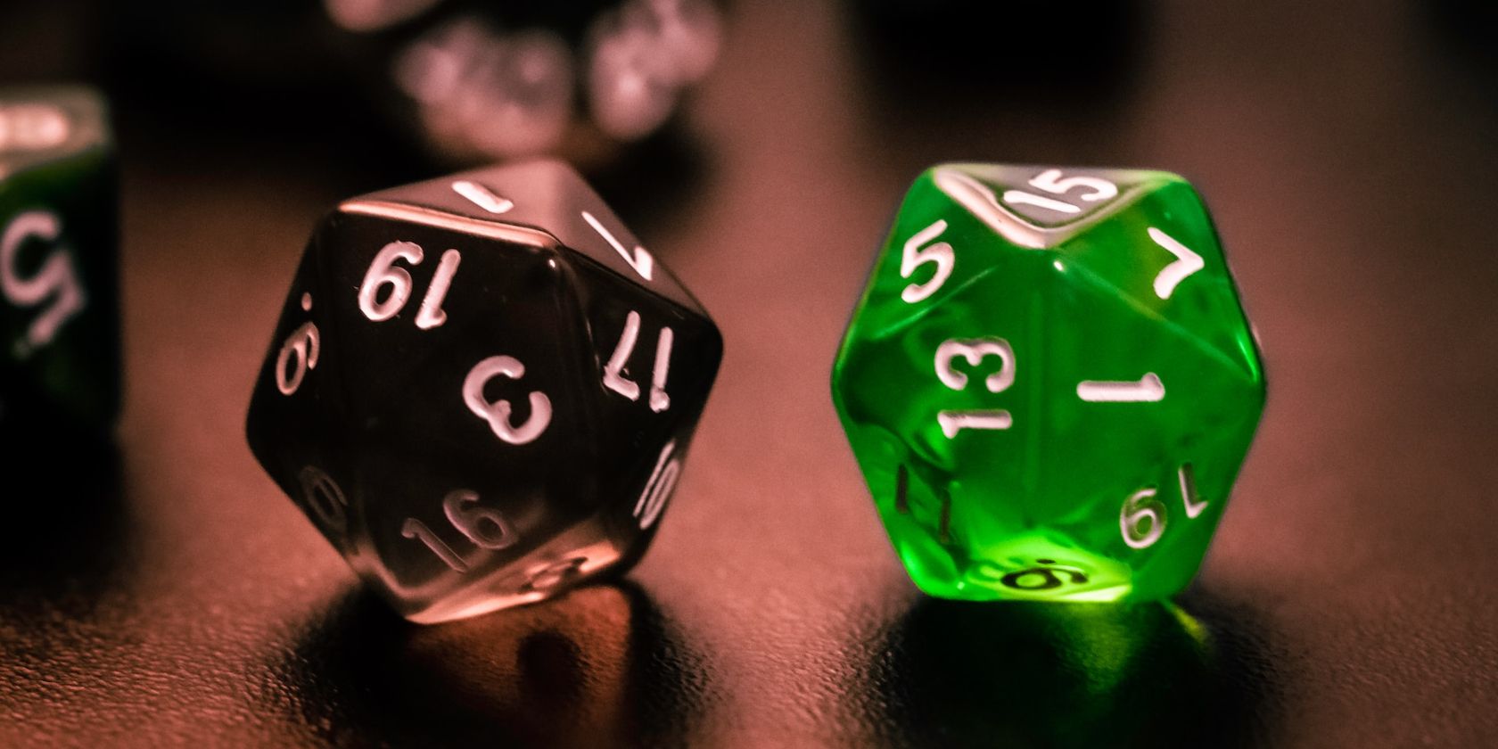 A black 20 sided die and a green 20 sided die side by side