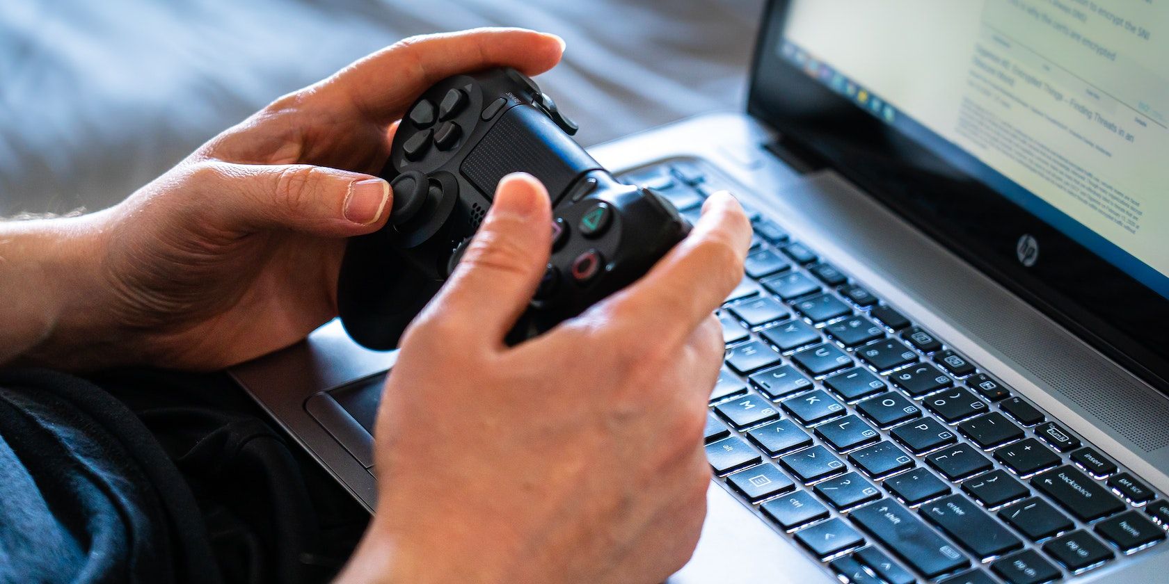 A black controller held in front of a laptop
