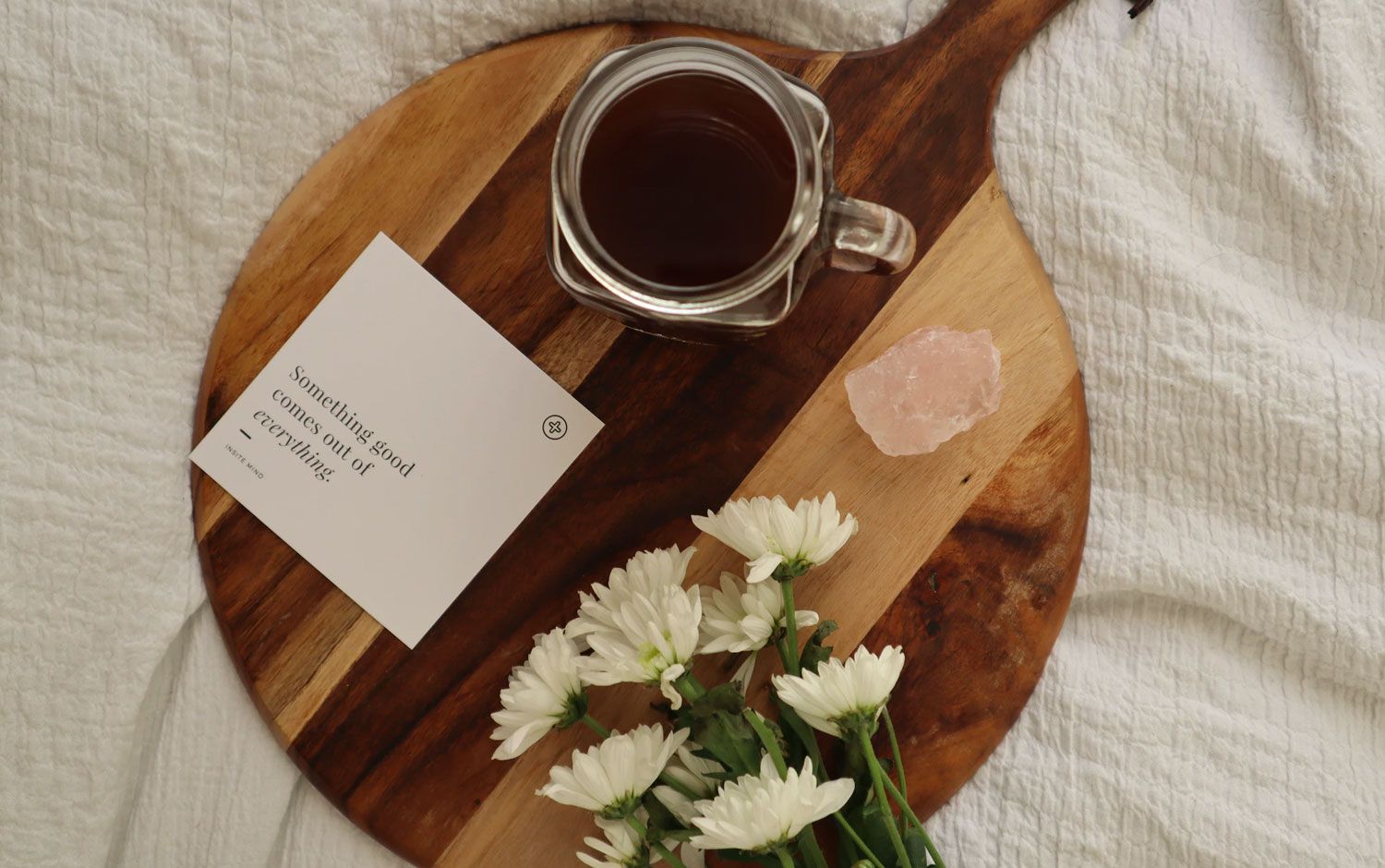 Tarjeta de afirmación en una bandeja de madera con café, flores y cristal.