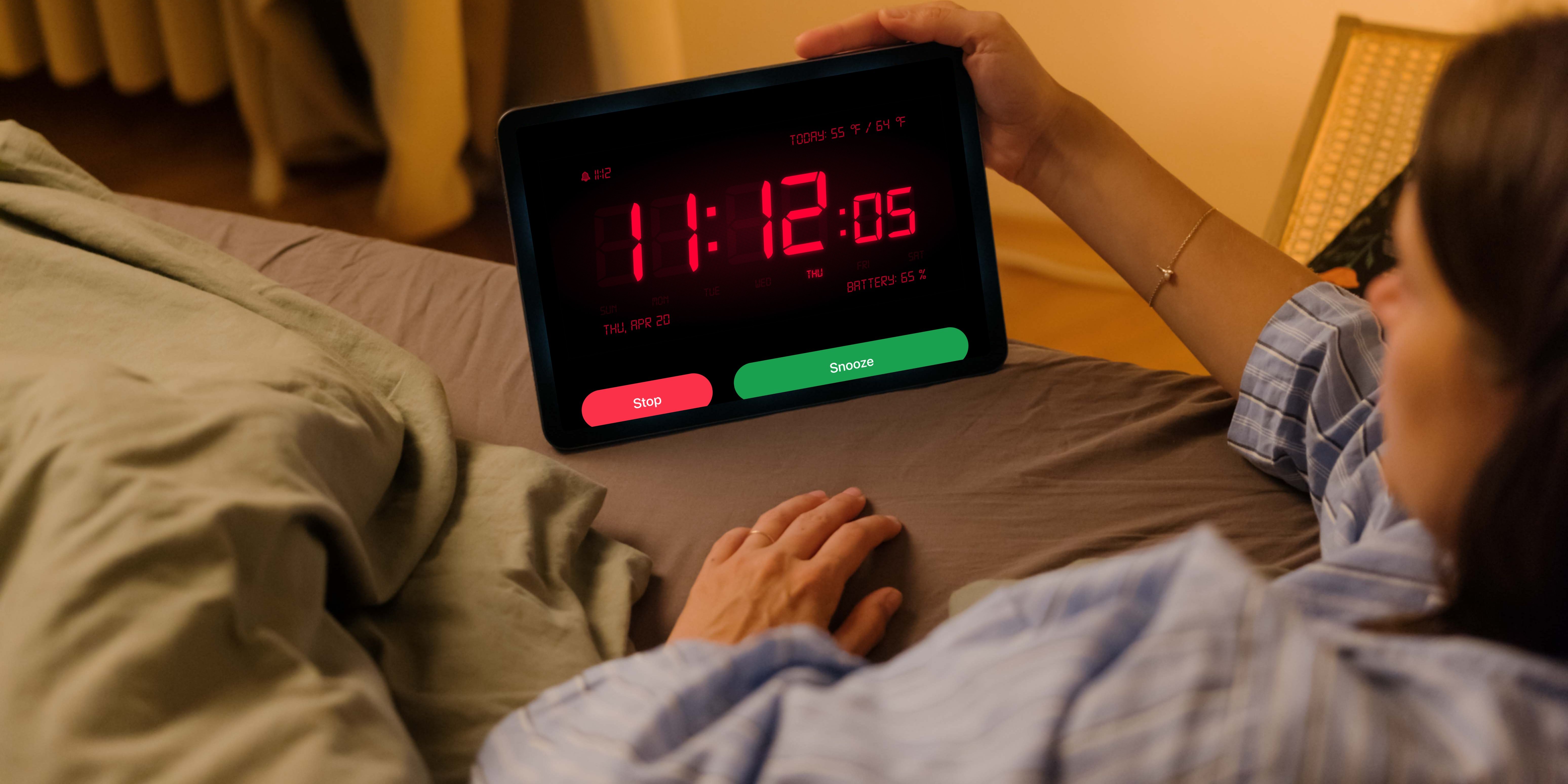A woman lying in bed, using the Alarm Clock HD app on iPad